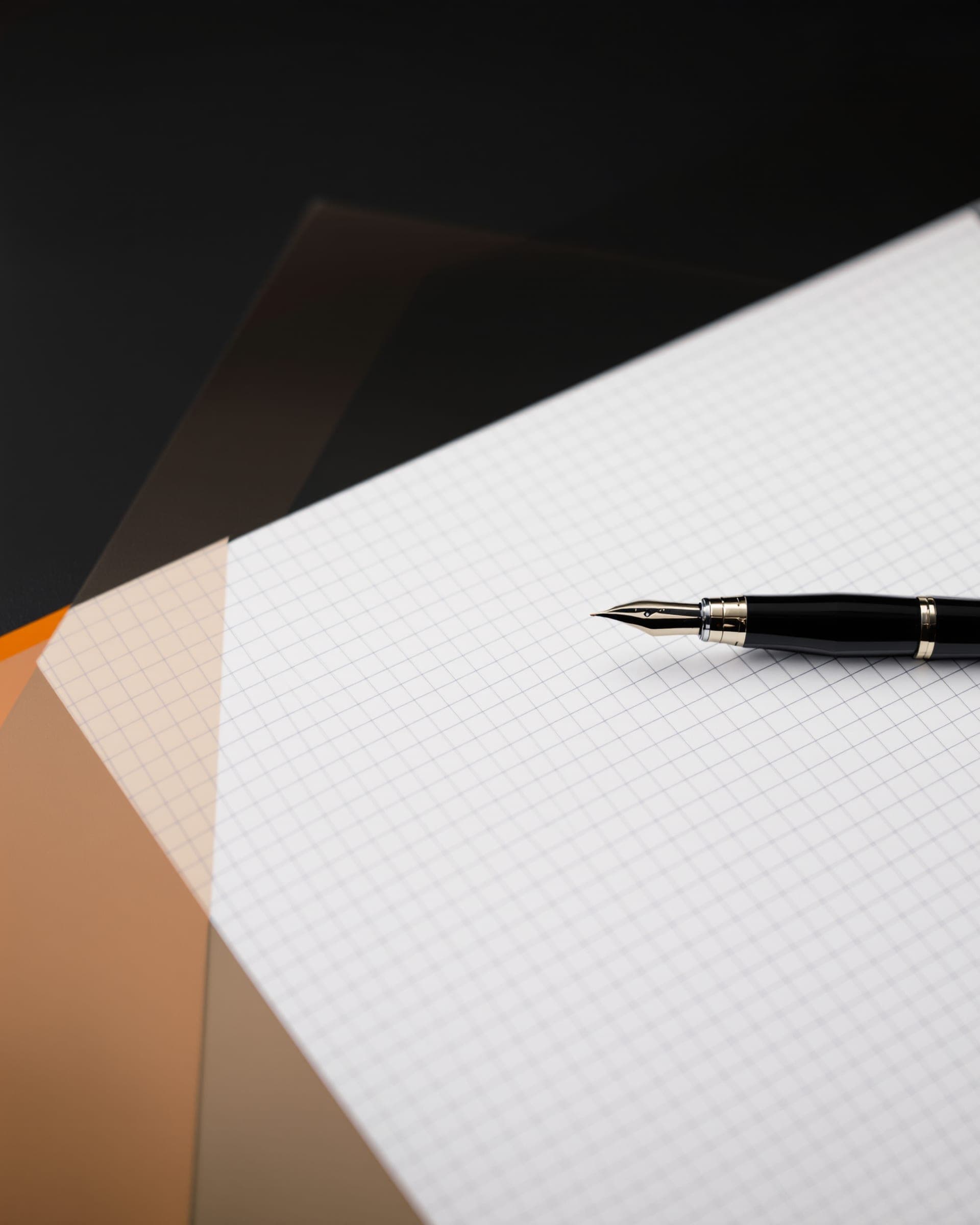 A fountain pen resting on blank graph paper beside an orange blotter.