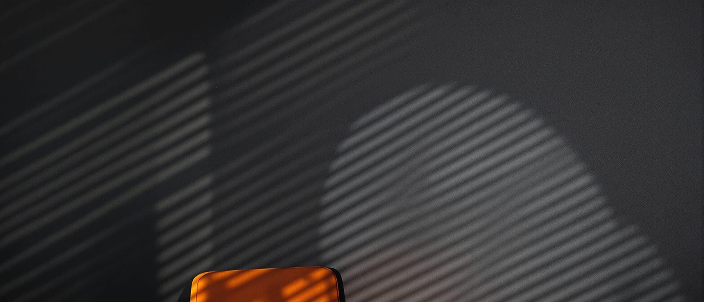 Stripes of light from window blinds across a dark office wall.