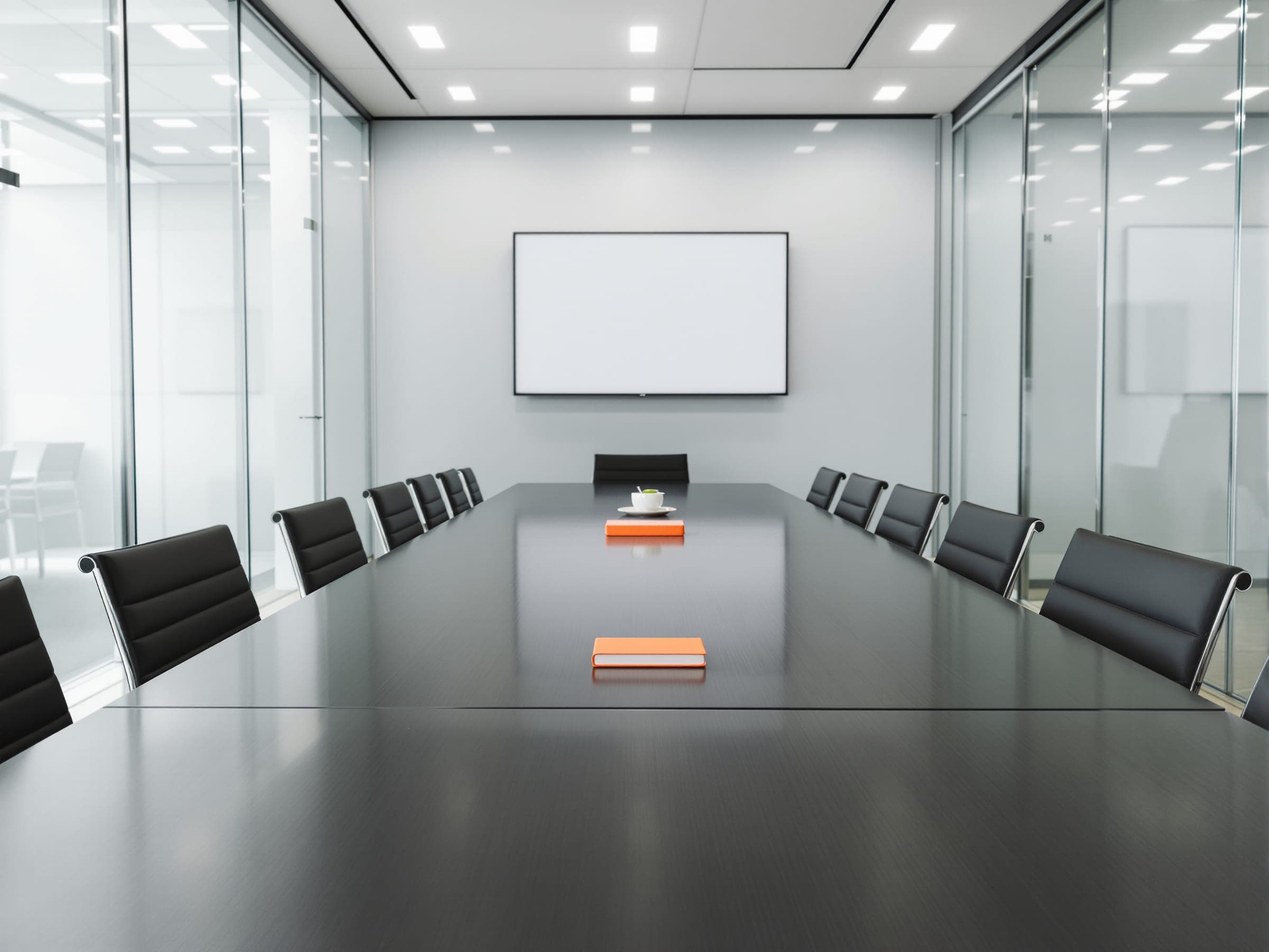 A bright glass-walled meeting room with a long table and an orange notebook.