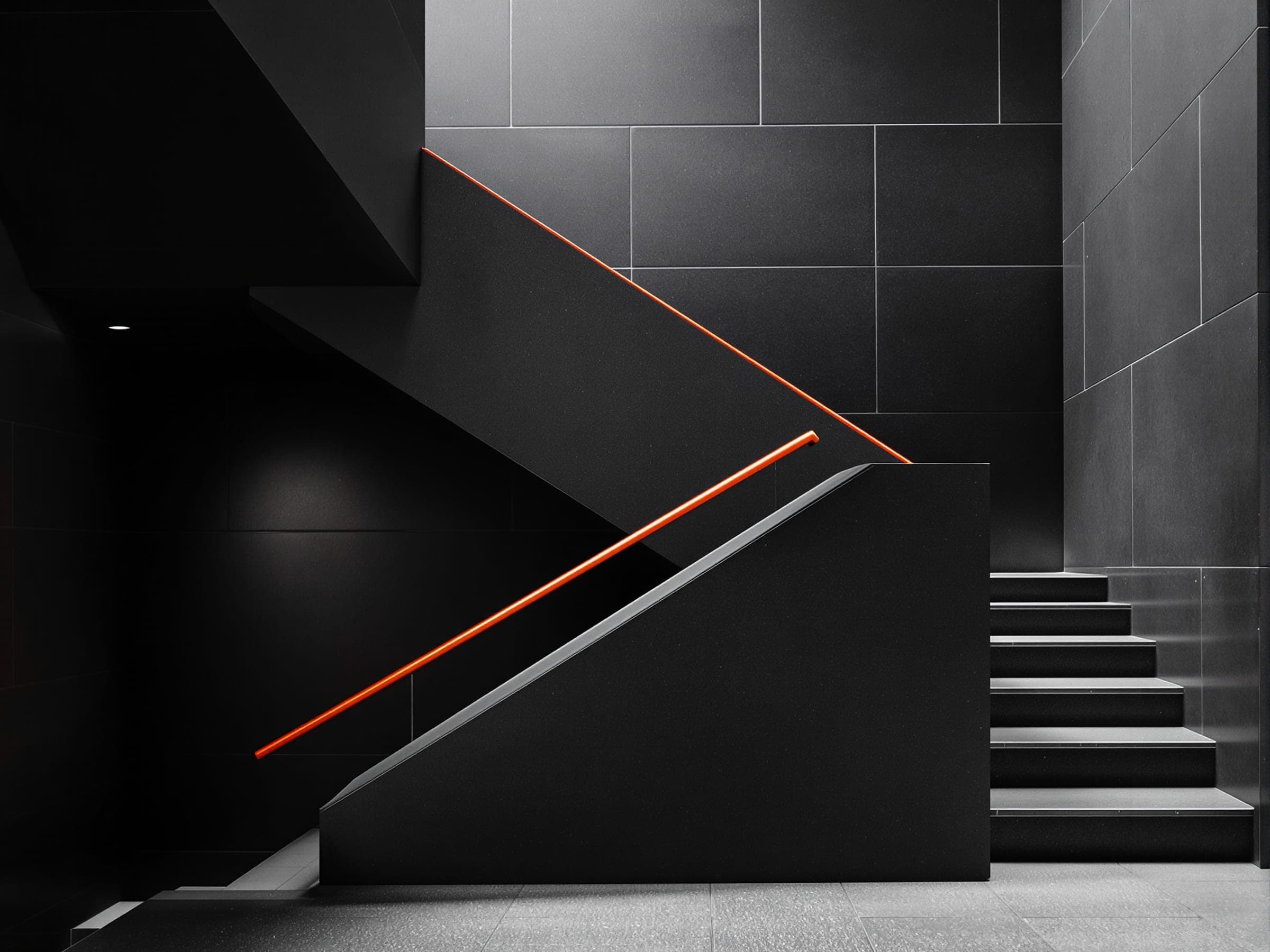 A dark concrete staircase with a thin orange handrail.