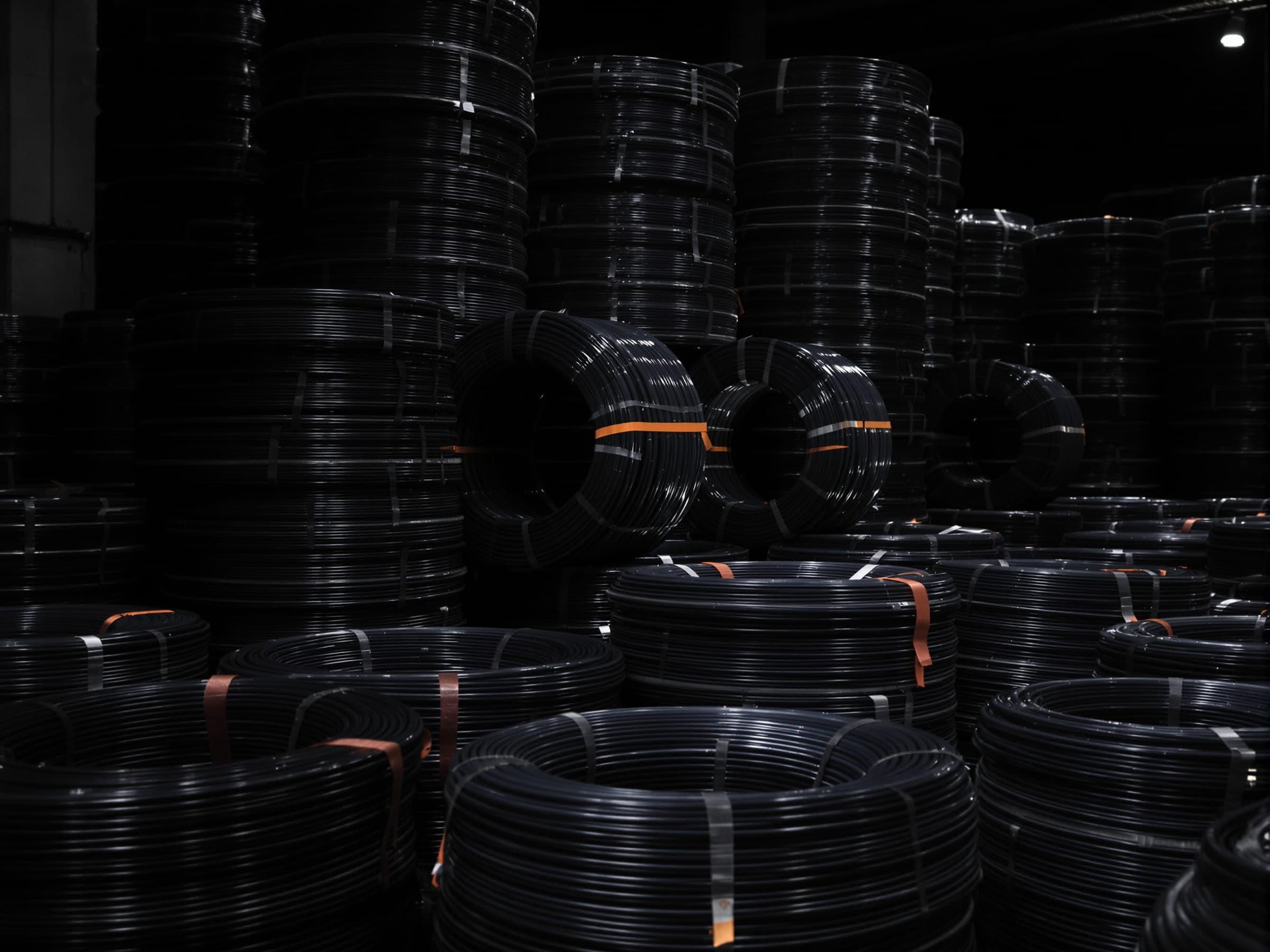 Stacks of dark industrial cable coils in a warehouse.