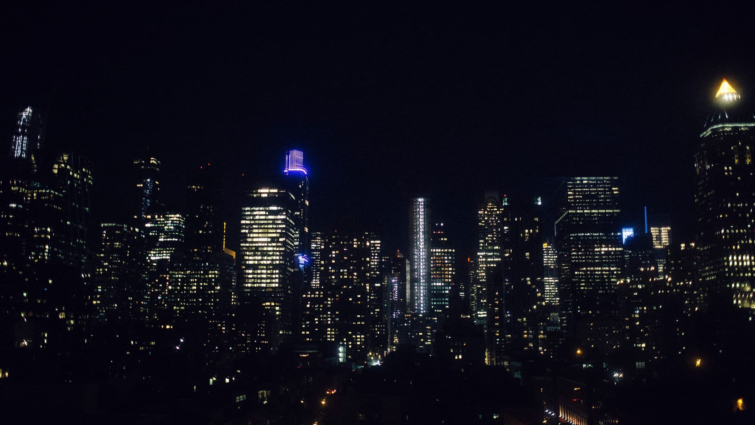 The New York skyline at night, office towers lit window by window against a black sky.