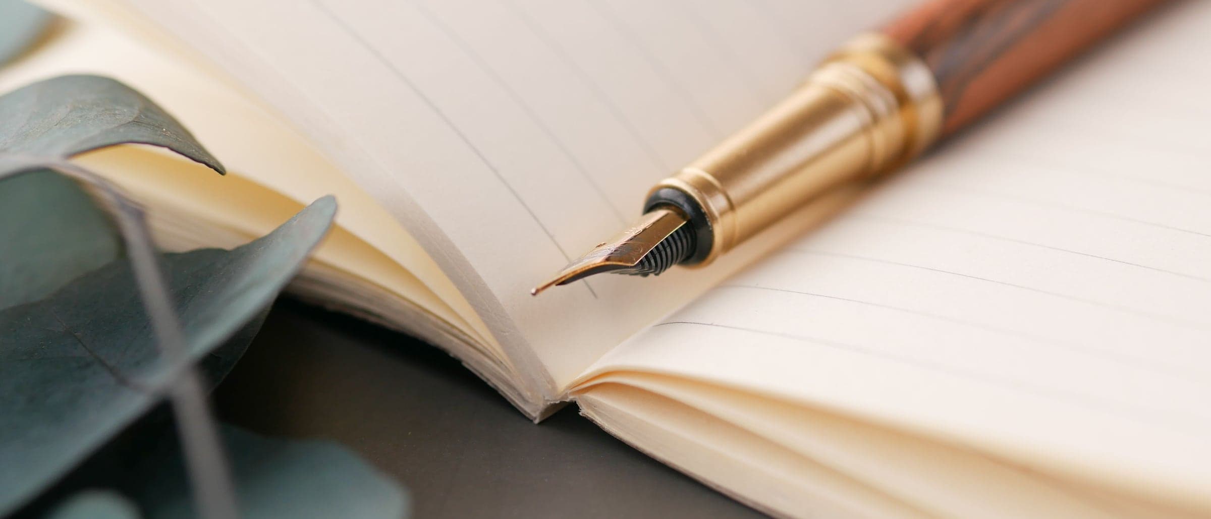 A fountain pen resting across the blank lined pages of an open notebook.
