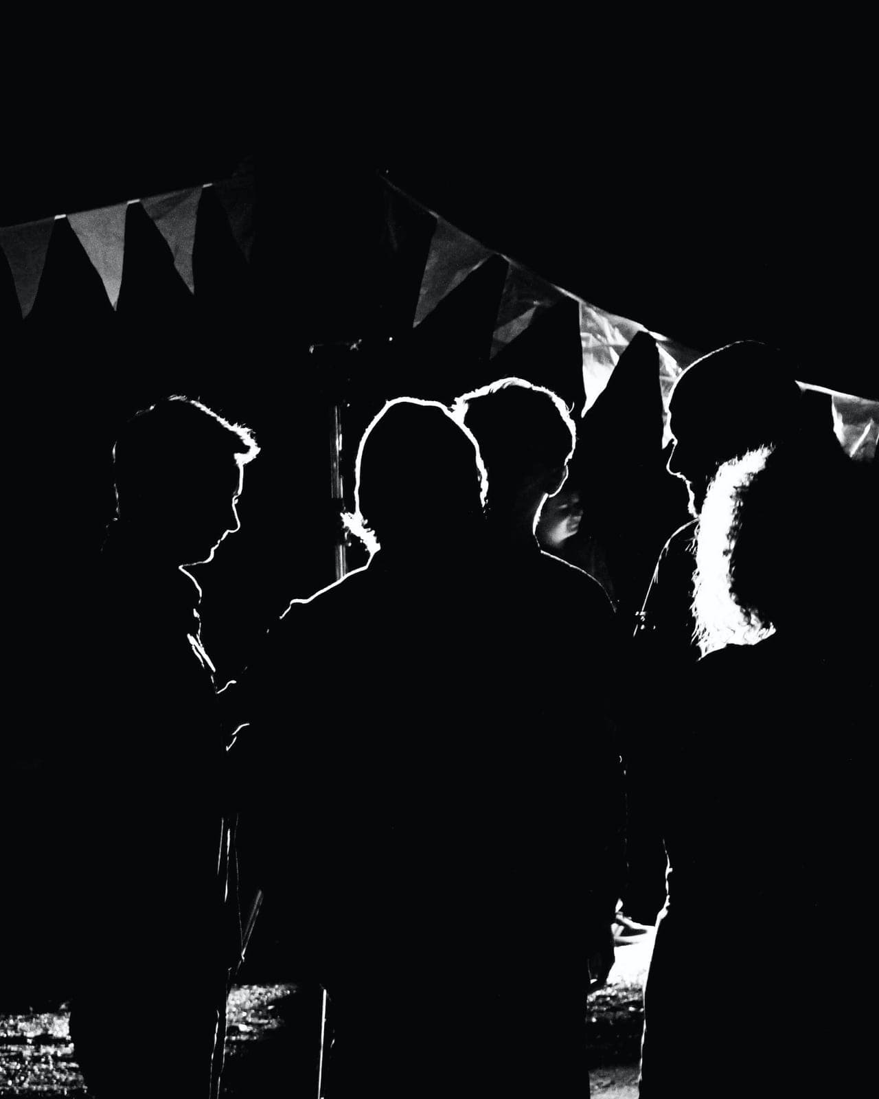 The silhouettes of a crowd at an evening event, lit from behind.